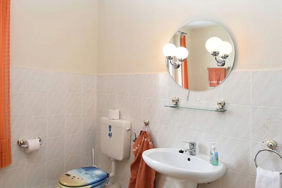 Badezimmer mit Toilette, Spiegel und Waschbecken